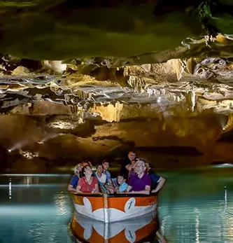 Turistas disfrutando de un paseo en barca por el río subterráneo de las Coves de Sant Josep, rodeados de espectaculares formaciones rocosas y agua cristalina. Experiencia única en cueva natural, Castellón.