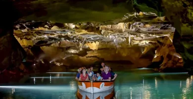Turistas disfrutando de un paseo en barca por el río subterráneo de las Coves de Sant Josep, rodeados de espectaculares formaciones rocosas y agua cristalina. Experiencia única en cueva natural, Castellón.