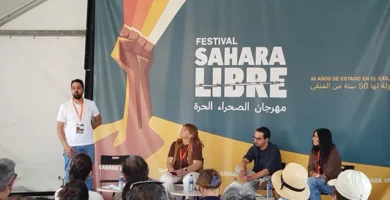Un grupo de personas participando en un panel de discusión en el Festival Sahara Libre. Al fondo, un cartel del festival con un puño en alto, simbolizando la lucha y el apoyo al pueblo saharaui. Evento de la Asociación Smara en La Vall La Vilavella.